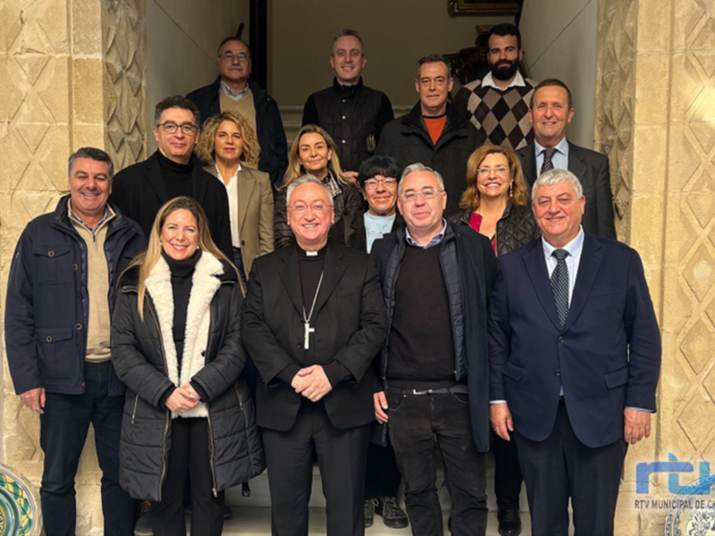 Grupo de personas posando en una entrada de edificio, incluyendo a un sacerdote y varios oficiales, posiblemente en un evento oficial.