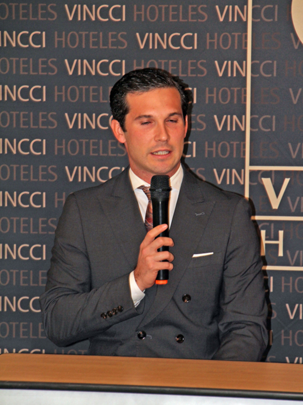Hombre en traje negro hablando en micrófono en evento de Vincci Hoteles
