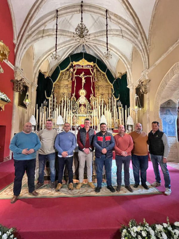 Grupo de hombres posando en el interior de una iglesia con una imagen religiosa en el fondo.