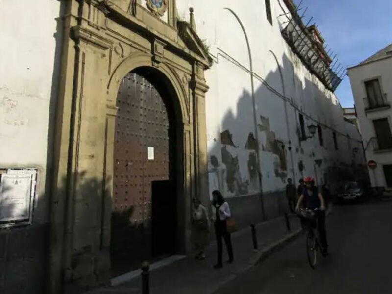 Puerta principal de un edificio histórico con puerta de metal y ventanas de balcón en una calle de la ciudad.