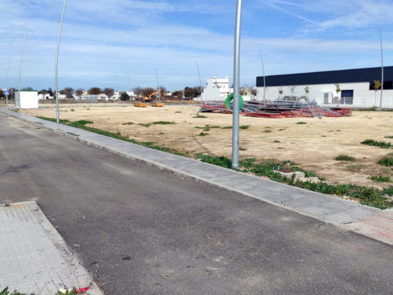 Desarrollo urbano en construcción con carretera y edificios en el fondo.