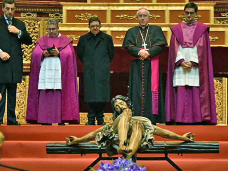 Representación de Jesús en la cruz durante una ceremonia religiosa en un interior ornado.