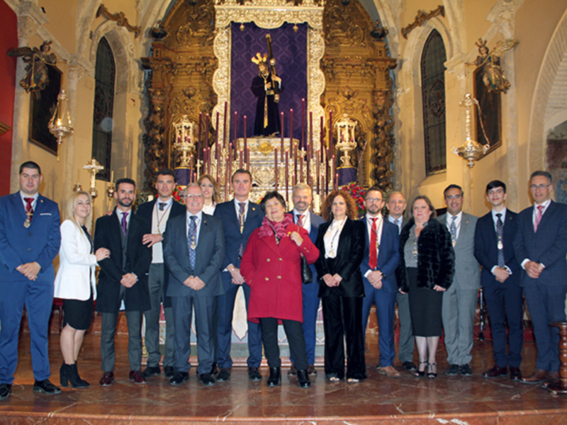 Gruppo di persone in abiti formali posano davanti a un altare ornato in una chiesa.