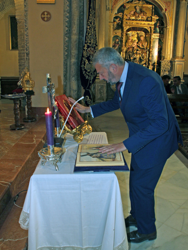 Un hombre en traje observa un libro antiguo en una iglesia con decoración barroca.