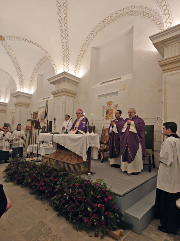 Eucaristía en una iglesia con sacerdotes en trajes litúrgicos y decoración floral en el altar.