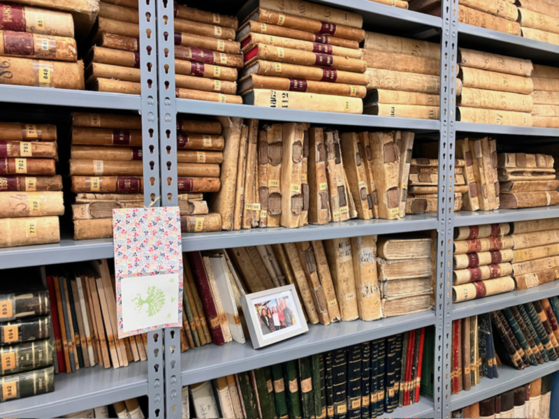 Estantería de libros antiguos con etiquetas y una foto familiar enmarcada.
