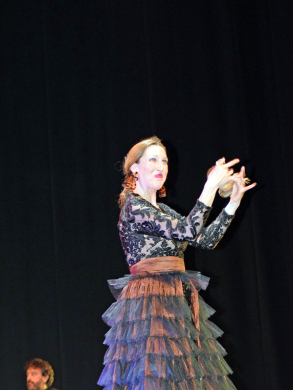 Actriz en vestido de flamenco, posando con elegancia en escenario.