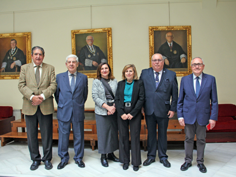 Reunión formal de autoridades en un salón decorado con retratos históricos.