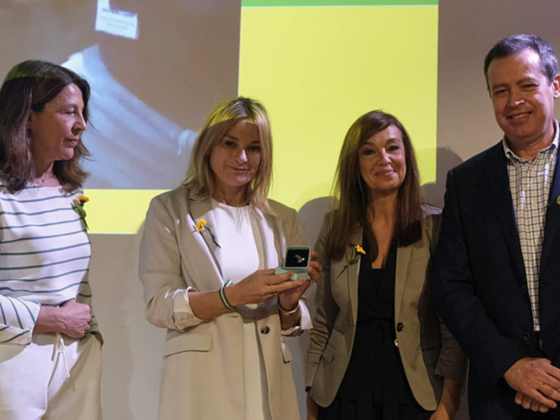 Premio entregado en ceremonia con tres mujeres y un hombre sonrientes, uno de las mujeres sostiene un trofeo.