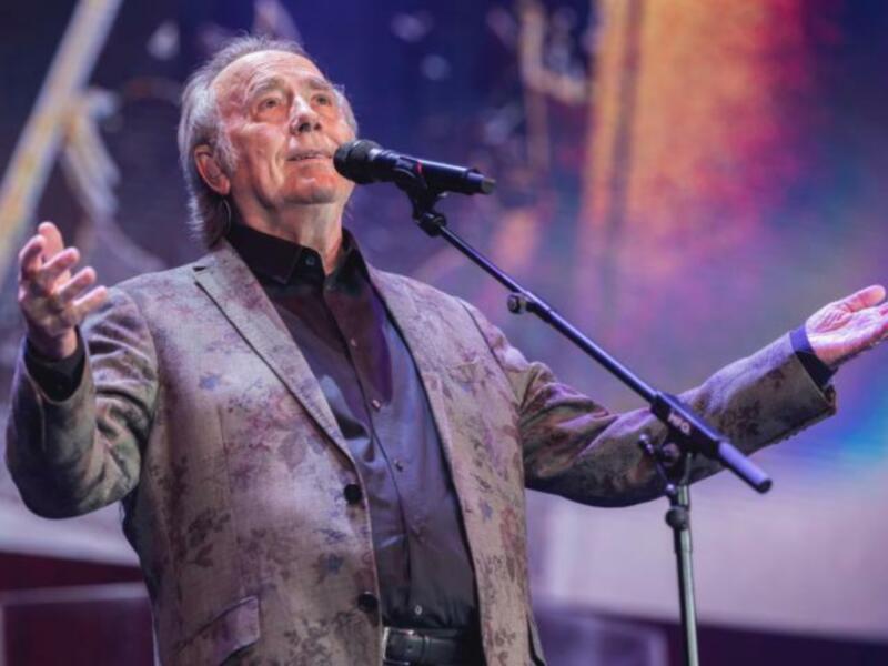 Artista cantando con pasión en un escenario iluminado.