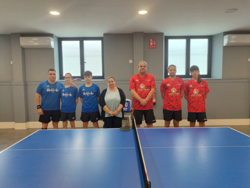 Equipo de tenis de mesa posando en una cancha de entrenamiento.