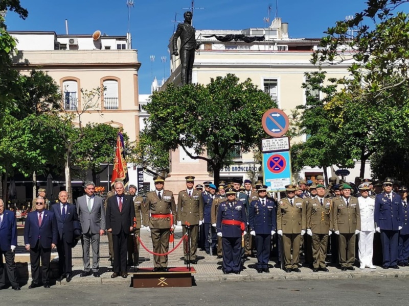 Ceremonia oficial con uniformes militares y civiles en una plaza con edificios históricos y estatua.
