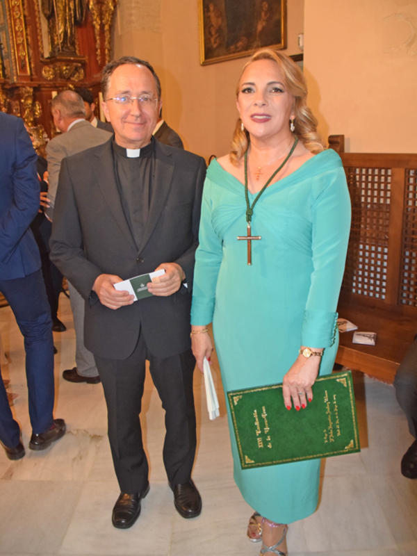 Persona religiosa y mujer con vestido verde en evento formal en iglesia.