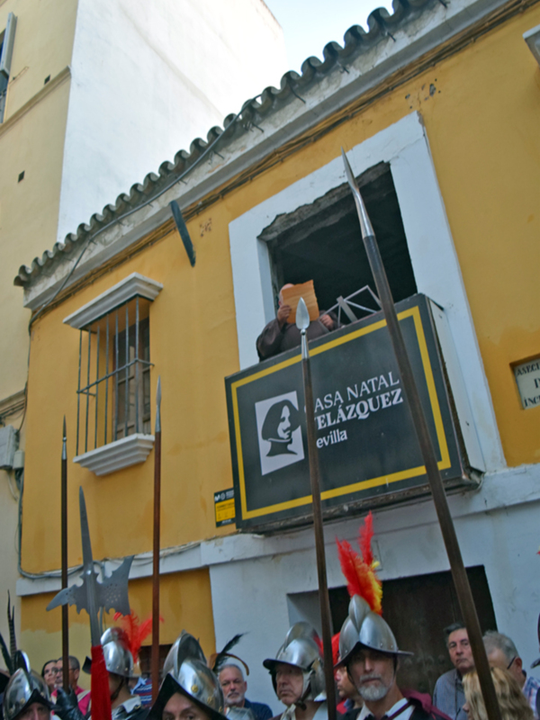 Recreación histórica con soldados en armadura y espectadores en una calle antigua de España.