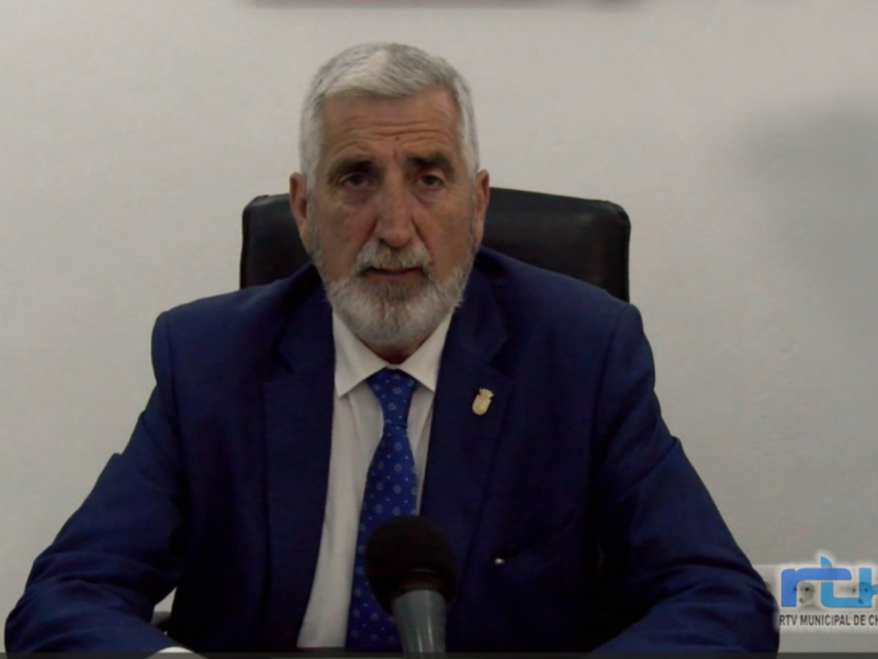 Un hombre con barba gris y traje azul está hablando en una conferencia de prensa.