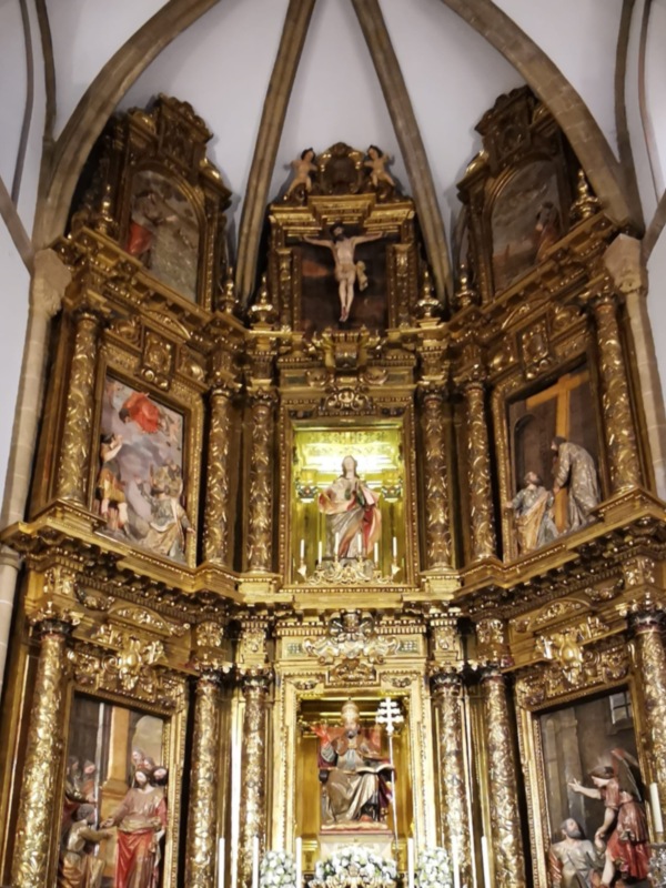 Altar gótico con retablo dorado y esculturas religiosas, destacando la figura central del Cristo crucificado.