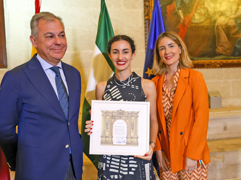 Celebración de un reconocimiento con una joven y dos autoridades en un entorno formal.