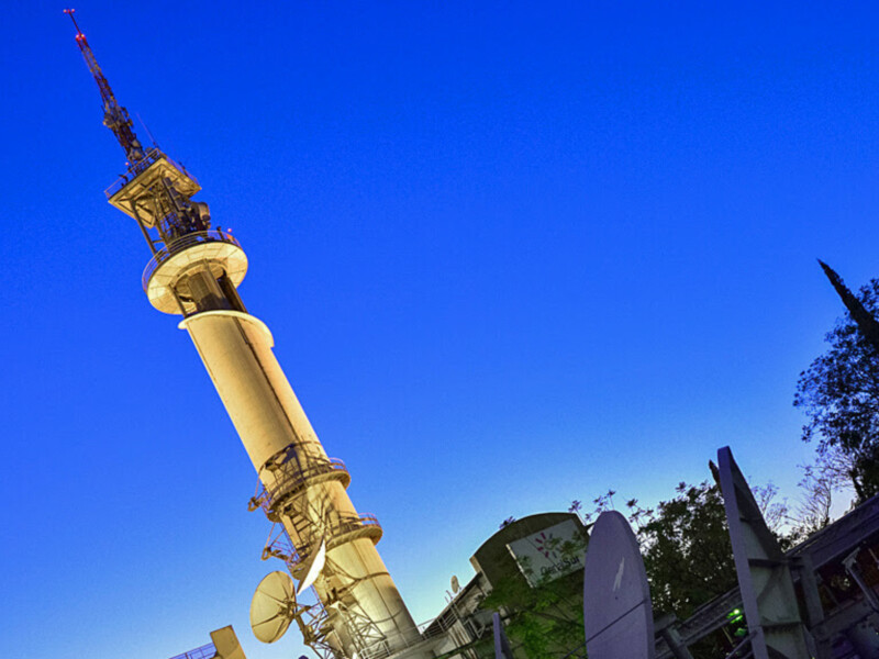 Una torre de telecomunicaciones con antenas y una estructura de telecomunicación en el cielo azul claro.