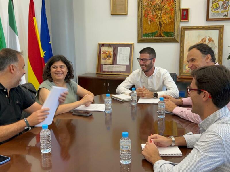 Reunión de trabajo en una oficina con banderas y marco decorativo en la pared.