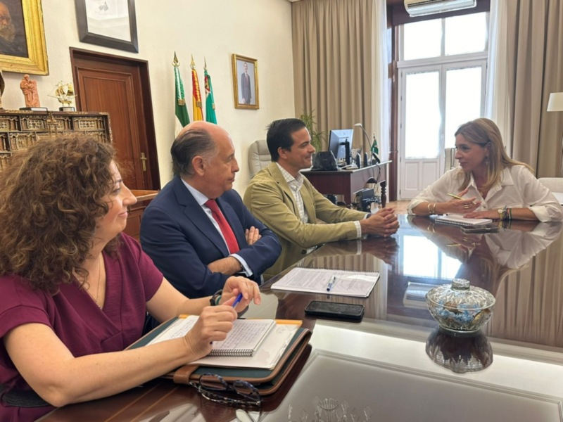 Reunión de trabajo en una oficina formal, con documentos y equipos de escritorio.