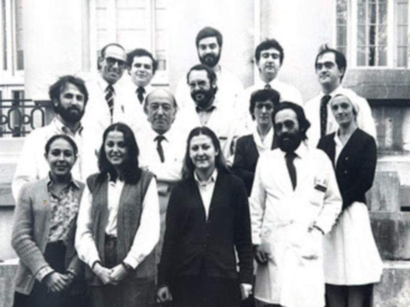 Grupo de personas posando en una foto antigua, posiblemente en un evento formal.