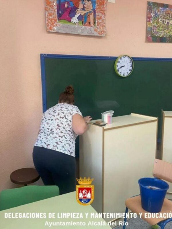 Personal de limpieza trabajando en la escuela, limpiando la pizarra y el mobiliario.