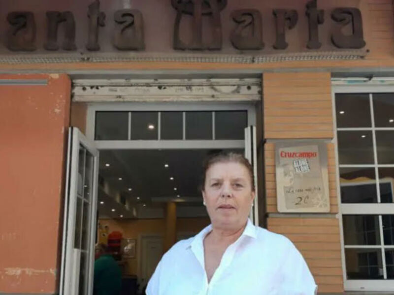 Una mujer frente a una entrada de un edificio con el nombre 'Santa Marta' en letras grandes sobre la puerta.