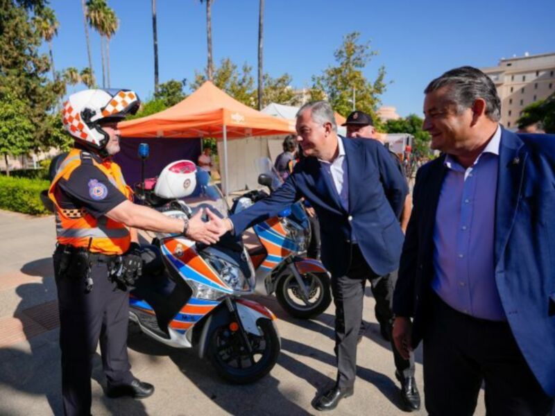 Un oficial de policía y un hombre en traje saludan cordialmente en un evento al aire libre.