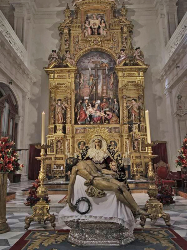 Interior de una iglesia con un altar barroco dorado y una escultura de la Pietà en primer plano.