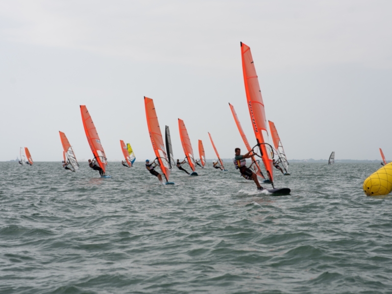 Competidores de windsurf en acción durante un evento deportivo en el mar.