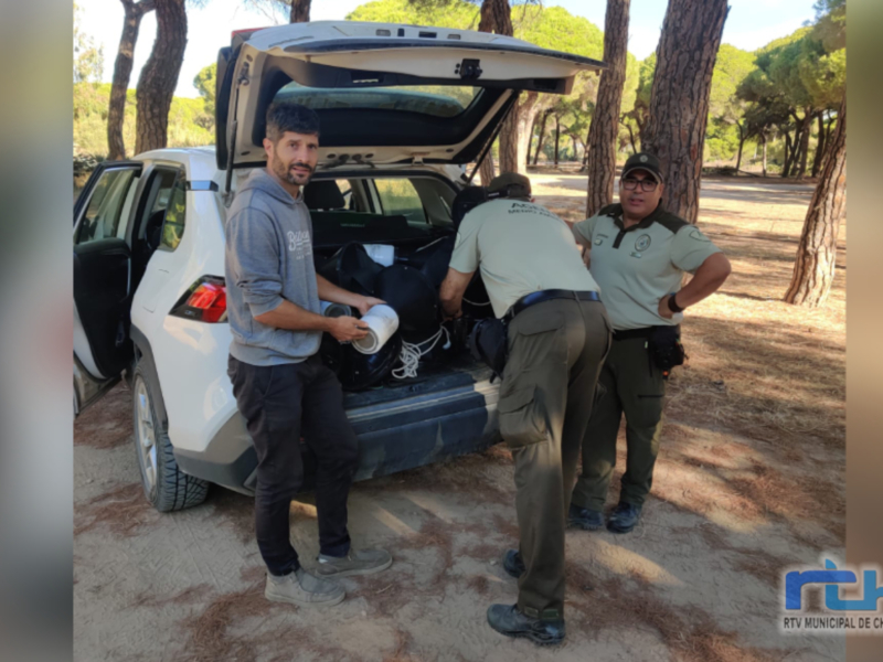 Personnel organizing supplies in a vehicle trunk in a forested area.