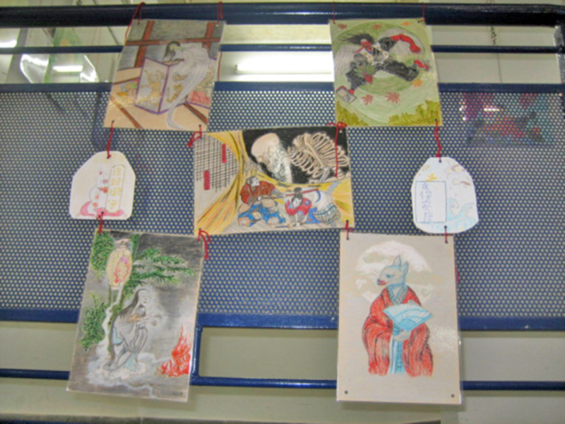 Dibujos tradicionales colgados en un espacio de exhibición, representando escenas y personajes históricos o mitológicos.
