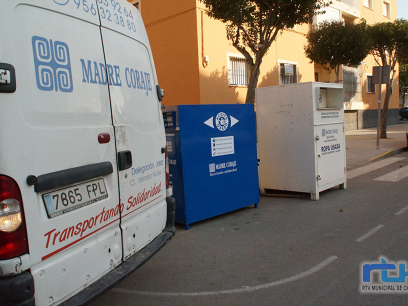 Un camión de recogida de ropa usada 'Madre Coraje' junto a contenedores de reciclaje en Chipiona, España.