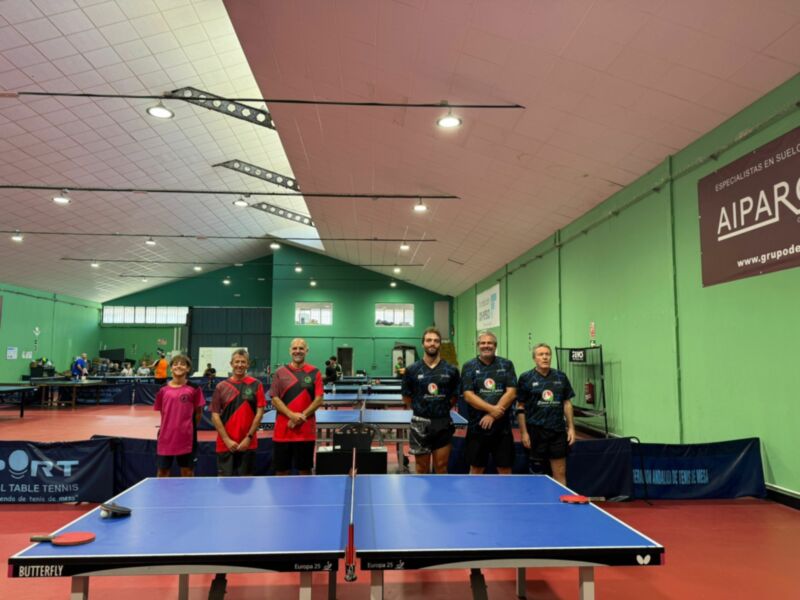 Equipo de tenis de mesa posando en una sala de deportes.