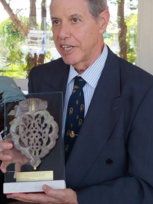 Hombre en traje sostiene un premio con un diseño floral en la parte superior.