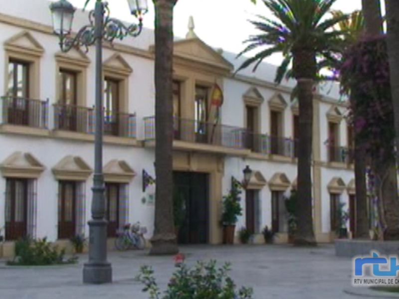 Edificio histórico con balcones y palmeras en Chipiona, España.