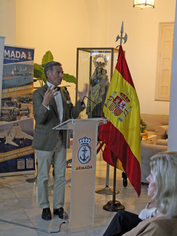 Discurso en evento militar con bandera española y estandarte de la Armada en el fondo.