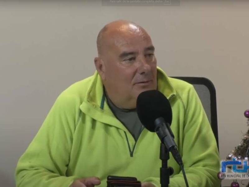 Un hombre en una conferencia de prensa, hablando en un micrófono, con un árbol de Navidad en el fondo.