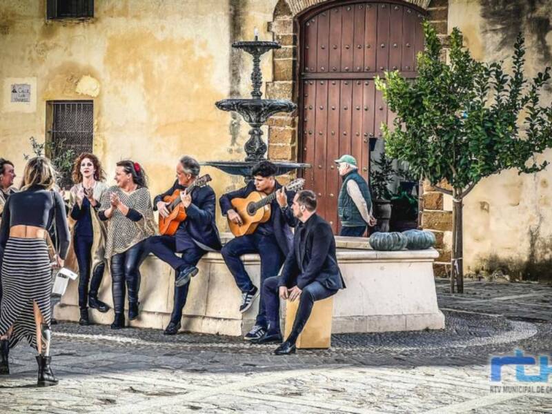 Músicos y espectadores disfrutan de una serenata en un patio histórico con fuente y arquitectura antigua.