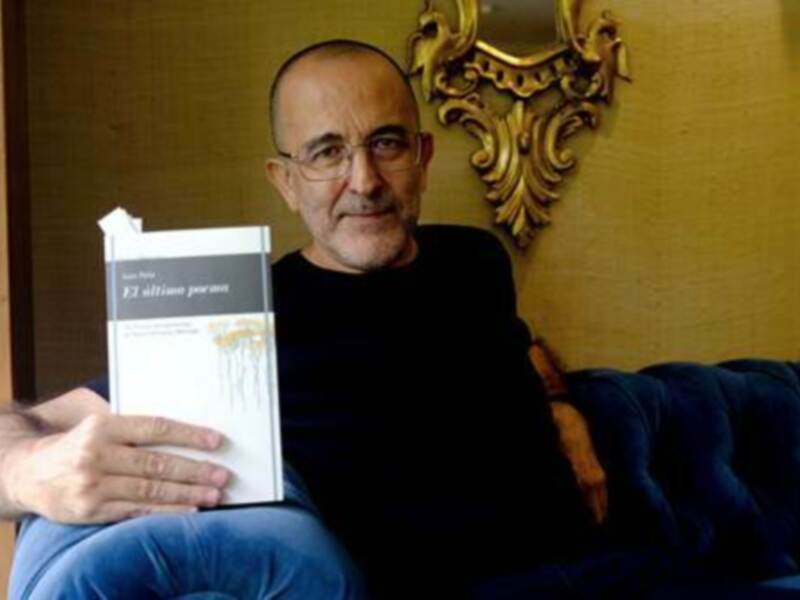Un hombre sostiene un libro titulado 'El último poeta' mientras se sienta en un sofá.
