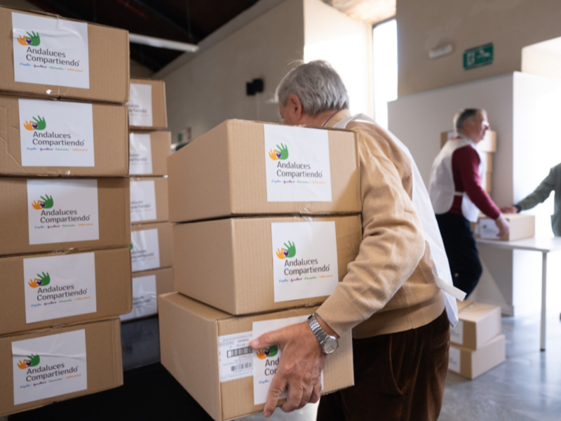 Andalucía en Acción: Voluntarios entregando paquetes de ayuda en un almacén.