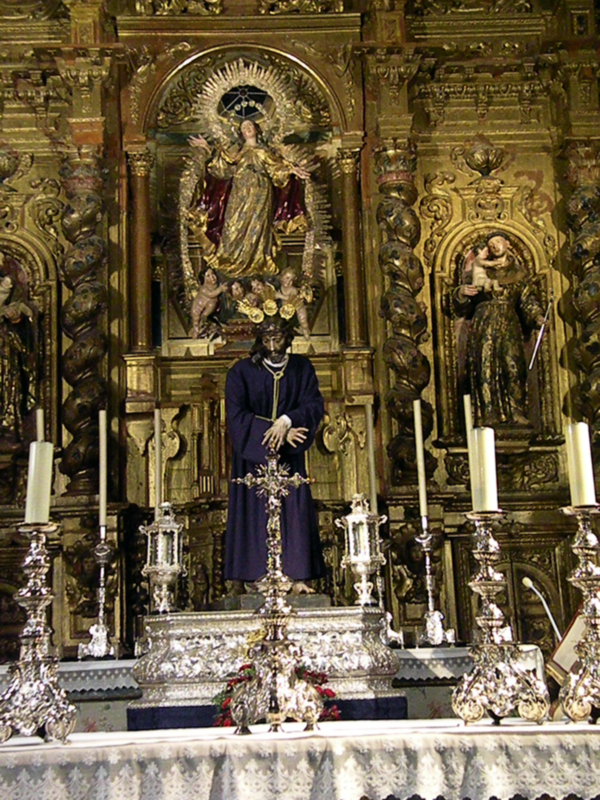 Altar con estatuas religiosas y ornamentos dorados, destacando una figura central rodeada de ángeles y adornos.