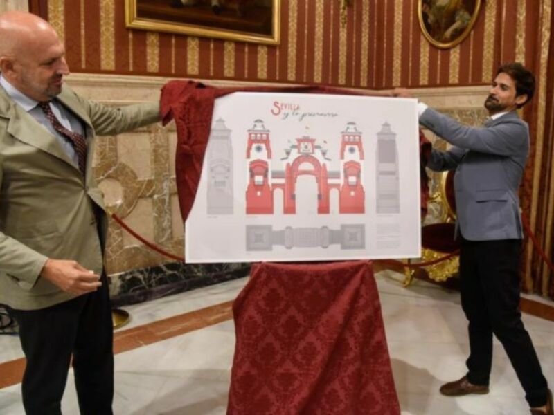 Un hombre en traje muestra un póster con la imagen de una fortaleza en un entorno decorado con cortinas y alfombras.