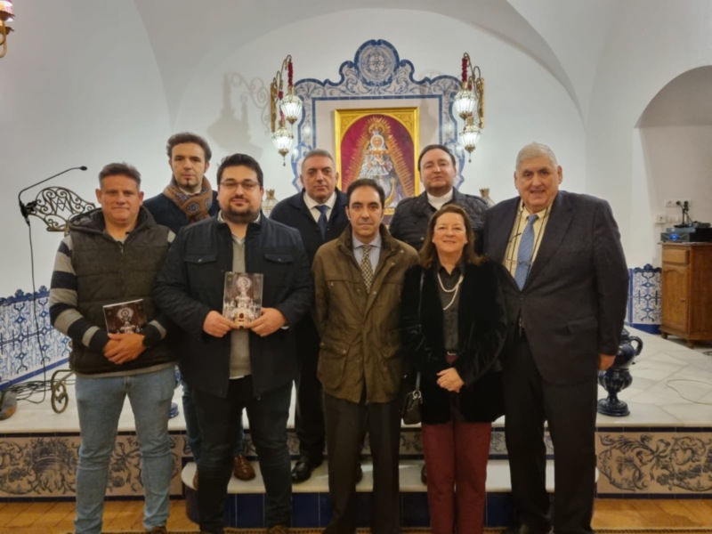 Grupo de personas posando en una sala decorada con azulejos y una imagen religiosa en el fondo.