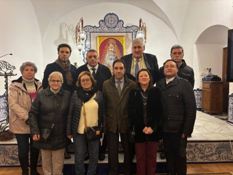 Grupo de personas posando en una sala con azulejos de estilo tradicional en el fondo.