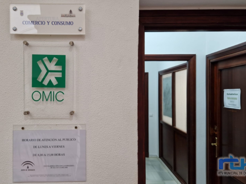 Placa informativa del OMIC (Oficina Municipal de Comercio y Consumo) con horario de atención al público de lunes a viernes de 8:00 a 15:00 horas.