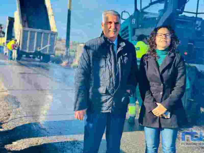 Dos personas posan frente a una grúa y un camión volcado en una carretera.