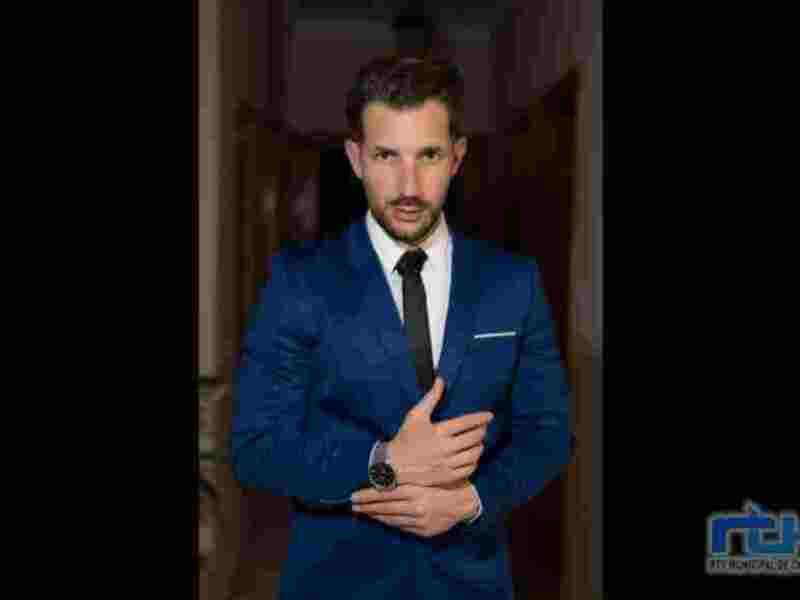 Elegante hombre en traje azul posando con elegancia.
