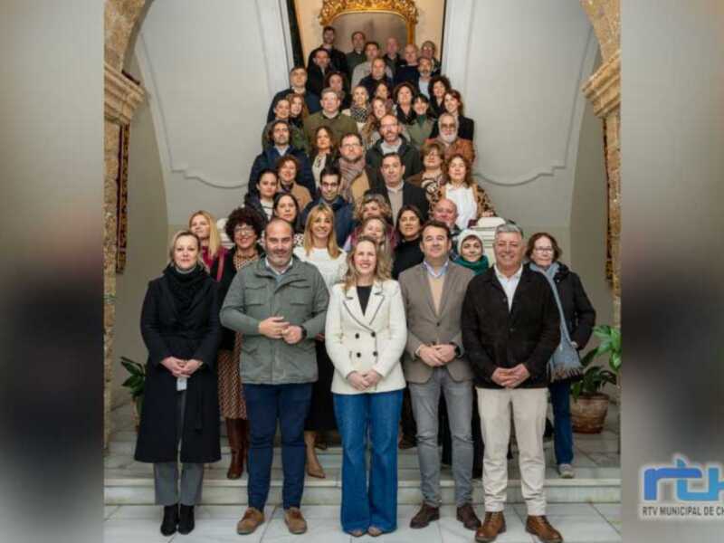 Una reunión de trabajo en un edificio histórico, con una mezcla de personas vestidas formalmente y casualmente, posando para una foto en una escalera de mármol. La imagen transmite un ambiente de colaboración y profesionalismo.