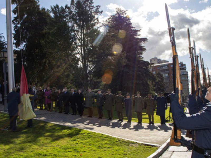 Desfile militar con uniformes y banderas en un entorno verde y soleado.